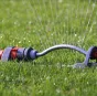 Lawn sprinkler on grass, connected to an automated irrigation control line